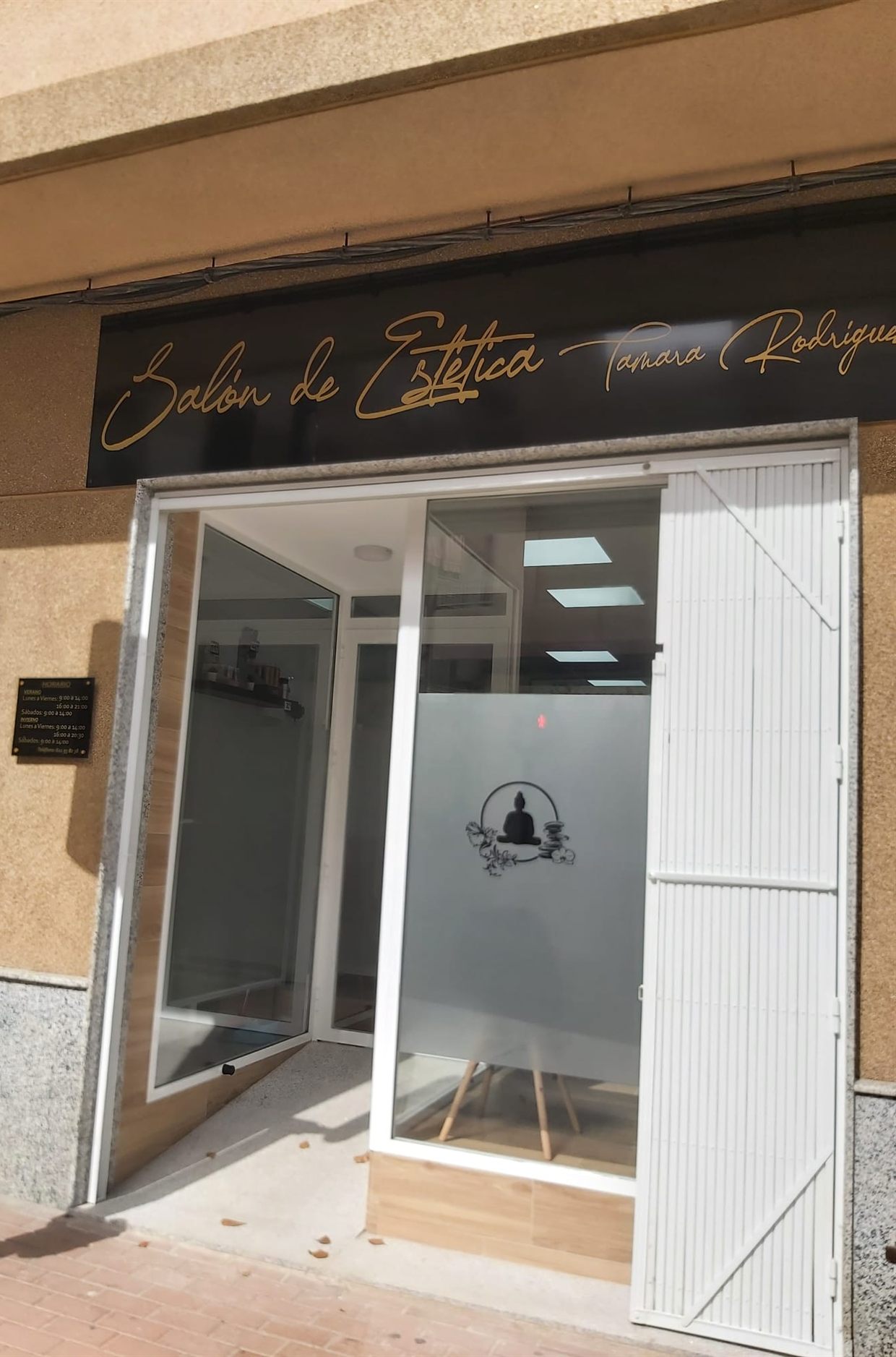 Escaparate del Salón de Estética Tamara Rodríguez en la calle Alfonso Ortega Carmona de Águilas, con el rótulo dorado sobre fondo negro.